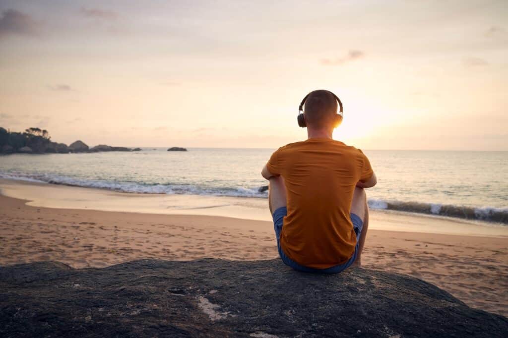 Rear view of man with headphones on beach